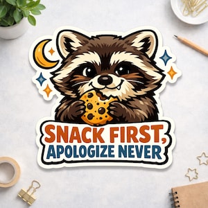 May include: A sticker featuring a cartoon raccoon eating a cookie. The raccoon is brown and white with a black nose and eyes. The sticker has the text "SNACK FIRST, APOLOGIZE NEVER" in orange and blue.
