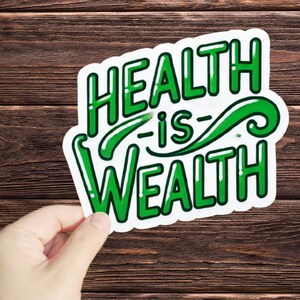 May include: A white sticker with green lettering that reads "HEALTH is WEALTH" on a brown wooden background.