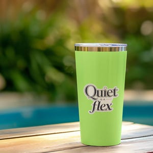 May include: A lime green insulated tumbler with a silver rim and lid. The tumbler has the phrase "Quiet is a flex" in a black and white sticker. The tumbler is sitting on a wooden surface with a blurred background of a pool and greenery.