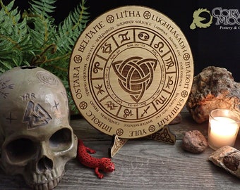 May include: A wooden wheel with a Celtic knot design in the center. The wheel is divided into eight sections, each representing a different month of the year. The wheel is labeled with the names of the eight sabbats, or holidays, of the Wheel of the Year. The wheel is on a wooden stand.