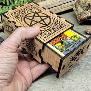 May include: Wooden box with a pentagram design on the lid and a tarot card inside. The card is labeled "The Magician."