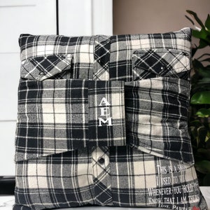 Pode incluir: Uma almofada de xadrez preto e branco com um bolso de cada lado. A almofada tem as iniciais "A B M" bordadas na frente. A parte de tr&aacute;s da almofada tem o texto "This is a shirt I used to wear. Whenever you hold it know that I am there. Love, Pawpaw."