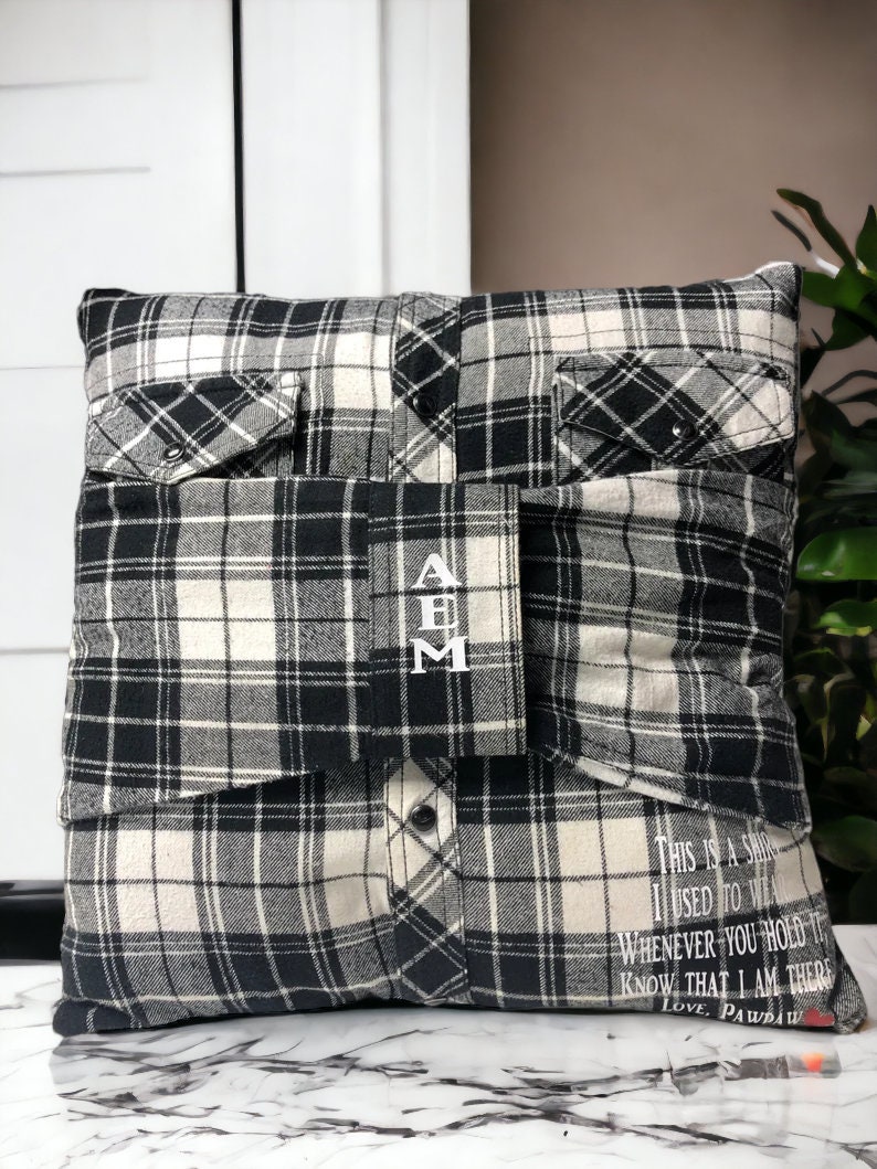 Pode incluir: Uma almofada de xadrez preto e branco com um bolso de cada lado. A almofada tem as iniciais "A B M" bordadas na frente. A parte de tr&aacute;s da almofada tem o texto "This is a shirt I used to wear. Whenever you hold it know that I am there. Love, Pawpaw."