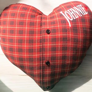 Puede incluir: Almohada en forma de coraz&oacute;n de tela a cuadros rojos y negros con el nombre "JOHNNIE" bordado.