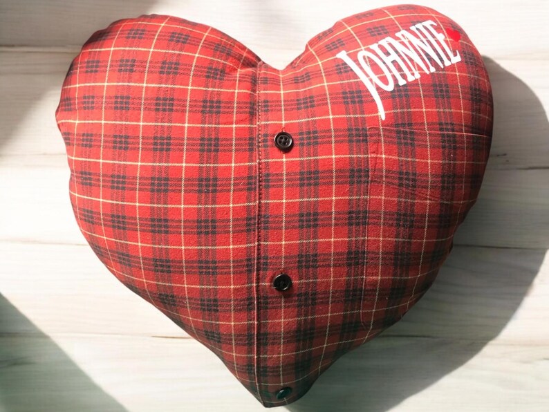 Puede incluir: Almohada en forma de coraz&oacute;n de tela a cuadros rojos y negros con el nombre "JOHNNIE" bordado.