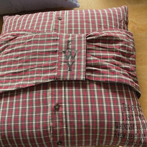 Pode incluir: Travesseiro xadrez vermelho e preto com um bot&atilde;o branco e as letras "EWY" bordadas na frente. O travesseiro tem uma cita&ccedil;&atilde;o nas costas que diz "Isso &eacute; algo que eu costumava dizer sempre que voc&ecirc; sabia que eu estava prestes a morrer."