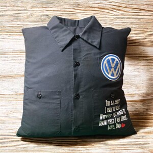 May include: A black button-down shirt pillow featuring a blue and white Volkswagen logo on the left chest. The right pocket area displays white text that reads: This is a shirt I used to wear whenever you hold it, know that I am there. Love, Dad.