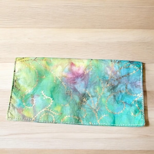 May include: A green, blue, and yellow fabric wallet with gold accents and a tie-dye pattern.