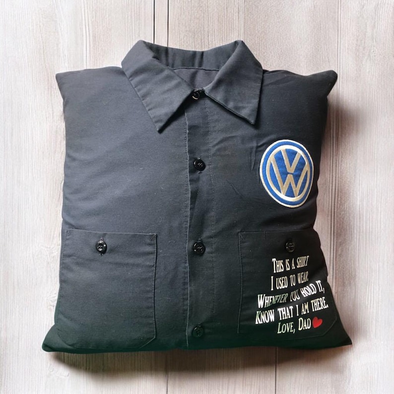 May include: A black button-down shirt pillow featuring a blue and white Volkswagen logo on the left chest. The right pocket area displays white text reading: This is a shirt I used to wear. Whenever you hold it, know that I am there. Love, Dad.