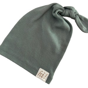May include: A sage green knotted baby hat with a white tag that says "fiz!"