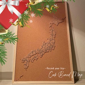 Peut inclure: Une carte du Japon en liège, de forme rectangulaire, encadrée de bois clair. La carte est détaillée avec les frontières des préfectures. Le texte sur le tableau indique "-Record your trip- Cork Board Map". Décorations festives en haut.