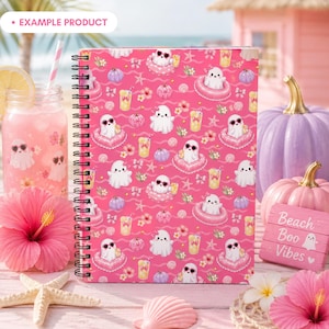 Example product mockup featuring a standing spiral notebook with the Pink Summer Ghost Pool Party seamless pattern on the cover, surrounded by lemonade, hibiscus flowers, seashells, starfish, pastel pumpkins, and beach decor. Cute Summerween stationery preview with ghosts, pink floats, bows, and girly Halloween vibes.