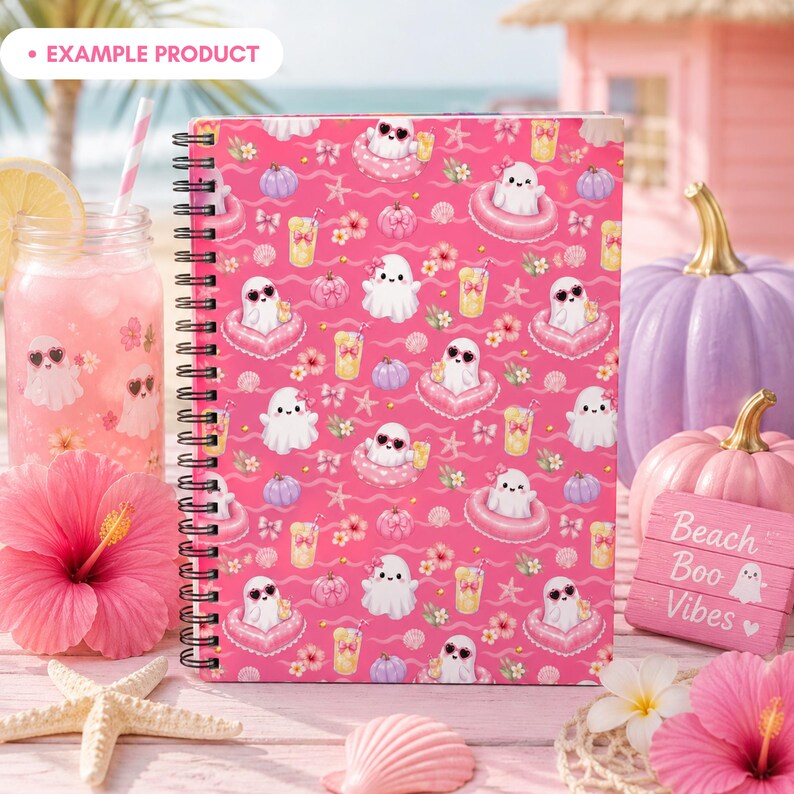 Example product mockup featuring a standing spiral notebook with the Pink Summer Ghost Pool Party seamless pattern on the cover, surrounded by lemonade, hibiscus flowers, seashells, starfish, pastel pumpkins, and beach decor. Cute Summerween stationery preview with ghosts, pink floats, bows, and girly Halloween vibes.