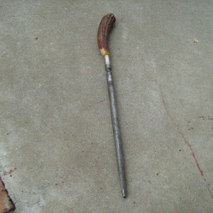 May include: A long, thin, metal knife sharpener with a brown and white antler handle.