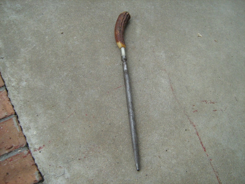 May include: A long, thin, metal knife sharpener with a brown and white antler handle.
