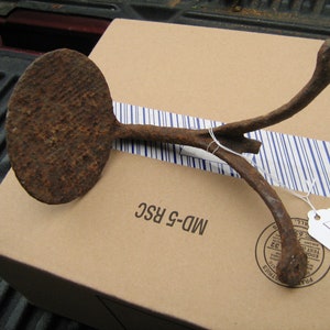 May include: A rusty metal object with a round, flat base and two curved arms. The object is labeled "MD-G RSC" and "2".