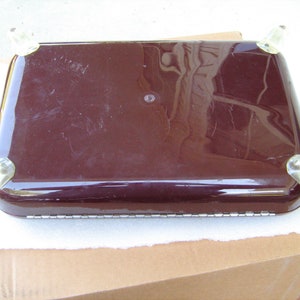 May include: A dark brown rectangular serving tray with clear plastic feet. The tray has a smooth, glossy finish.