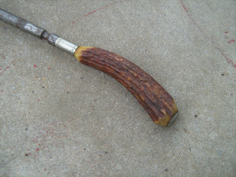 May include: A vintage, metal and antler handled tool with a silver band. The tool has a brown antler handle with a silver cap.