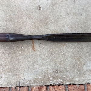 May include: A vintage wooden and metal chisel with a dark brown wooden handle and a black metal blade.