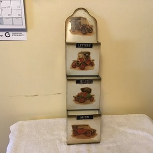 May include: A white metal mail sorter with four compartments. Each compartment has a vintage car image and a label: "Letters", "Bills", "Misc."