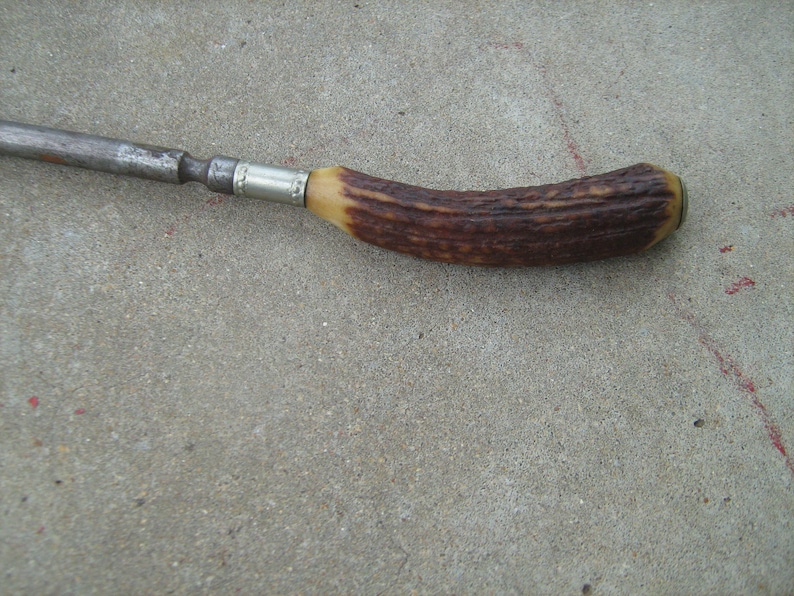 May include: A vintage, metal and antler handled tool with a silver band. The tool has a dark brown antler handle with a silver band.