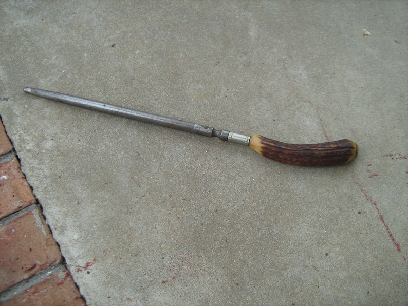 May include: A metal knife sharpener with a brown and tan antler handle.