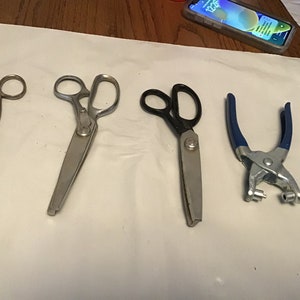 Peut inclure: Quatre outils pour l'artisanat&nbsp;: une paire de ciseaux argent&eacute;s, une paire de ciseaux &agrave; tissu argent&eacute;s, une paire de ciseaux &agrave; tissu noirs et un poin&ccedil;on manuel bleu et argent.
