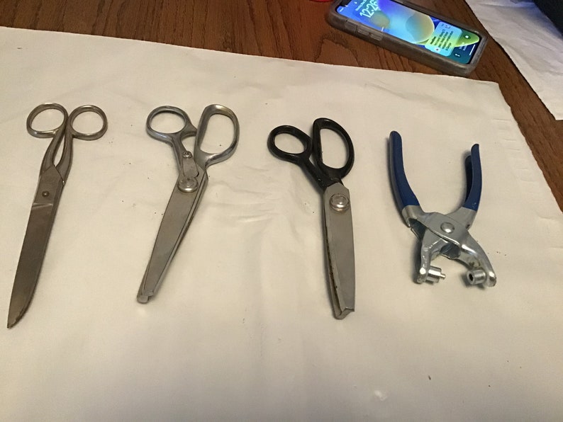 Peut inclure: Quatre outils pour l'artisanat&nbsp;: une paire de ciseaux argent&eacute;s, une paire de ciseaux &agrave; tissu argent&eacute;s, une paire de ciseaux &agrave; tissu noirs et un poin&ccedil;on manuel bleu et argent.