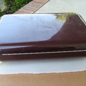 May include: A dark brown rectangular box with a decorative silver trim around the edge. The box has four clear plastic feet.