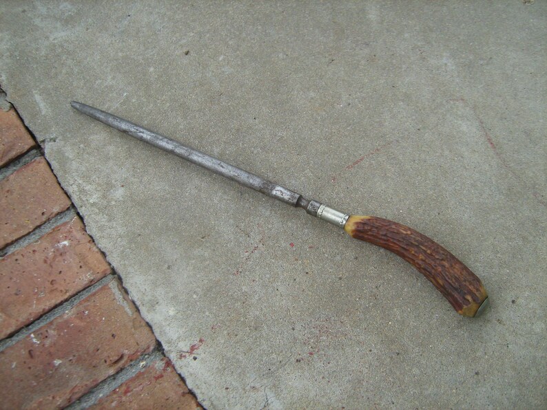 May include: A long, silver steel knife sharpener with a brown antler handle.