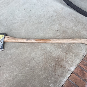 May include: A wooden-handled axe with a black metal head. The axe has a yellow sticker on the head that says "4 lbs". The handle is labeled "Collins Axe".