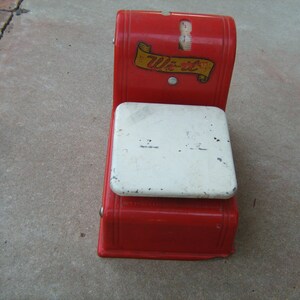 May include: Red and white toy scale with a white platform and a red base. The scale has a banner that says "Weigh-It" in black letters.