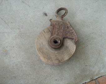 Antique rusty fresh from the farm cast iron pulley with wood wheel