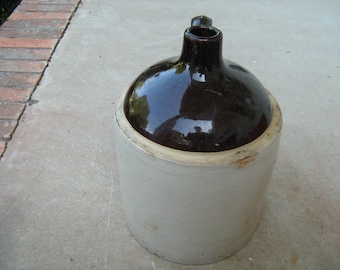 May include: A brown and white glazed stoneware crock with a wide mouth and a handle.