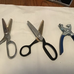 Peut inclure: Quatre outils pour la couture et l'artisanat, dont deux paires de ciseaux &agrave; tissu argent&eacute;s et noirs &agrave; lames dentel&eacute;es et une poin&ccedil;onneuse &agrave; &oelig;illets en m&eacute;tal bleu.