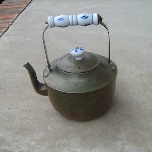 May include: A green copper kettle with a white porcelain handle and knob. The kettle has a speckled green finish.