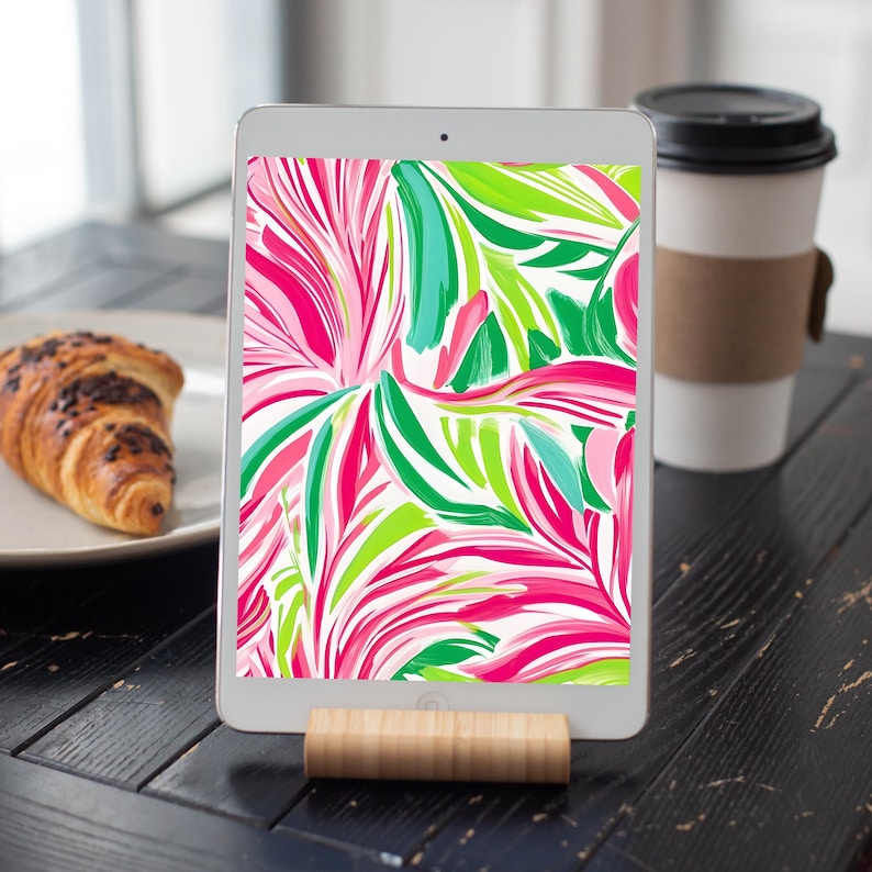 May include: A tablet displaying a digital illustration of pink, green and blue abstract floral patterns on a white background.