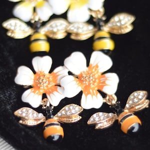 Bijenbroche met bloemen: emaille bloemspeld met hangende bijen