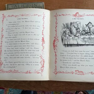 May include: Open book with illustrations and text from "Alice in Wonderland." The pages show a drawing of a tea party with Alice, the Mad Hatter, and the March Hare. The text includes the phrase "A Mad Tea Party."
