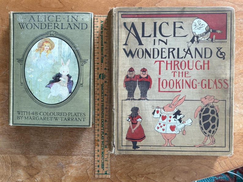 May include: Two vintage books, "Alice in Wonderland" and "Alice in Wonderland & Through the Looking-Glass", with illustrations. The first book is green with an oval illustration of Alice and a rabbit. The second book has illustrations of characters from the story.