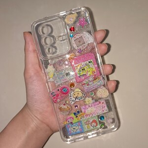 Transparent resin phone cover with sparkly silver glitter and adorable pastel motifs like pudding, milkshake, and anime characters.
