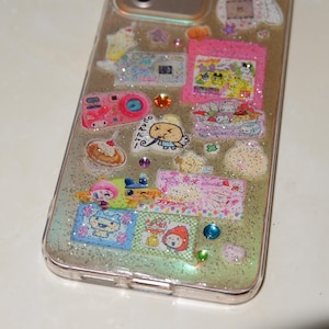 A detail close up of handmade transparent resin case featured with Japanese Harajuku and Y2K style stickes with silver and hologram glittery effect