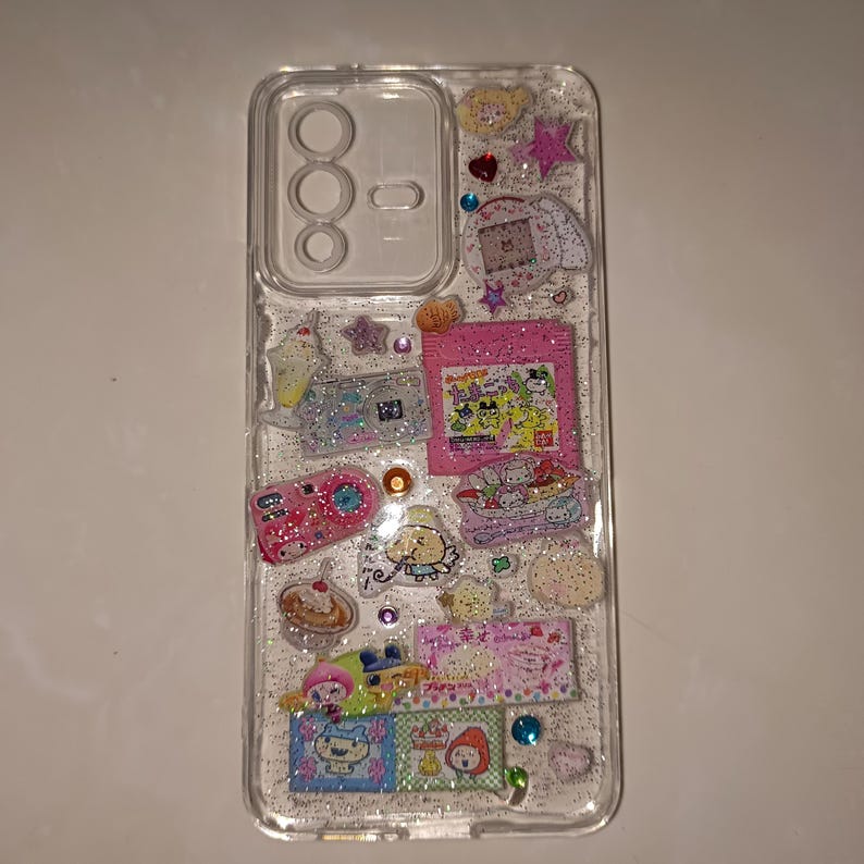 Glittery Y2K kawaii phone case with resin embedded rhinestones, candy, stars, and pink camera stickers.