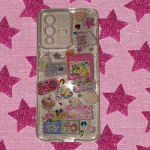 Clear resin phone case with kawaii Japanese stickers, glittery silver background, and colorful rhinestones in Y2K aesthetic style.