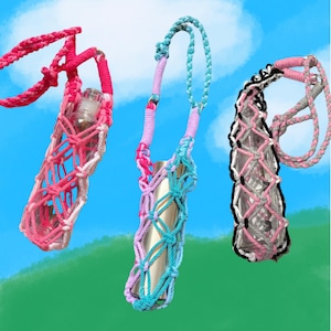 May include: Three crocheted bottle holders with different color combinations. The holders are made with pink, blue, and white yarn. Each holder has a different bottle inside, one is clear glass, one is silver, and one is clear glass with a pink and black design.