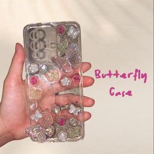 May include: Clear phone case with a butterfly theme. The case is decorated with silver and pink butterflies, rhinestones, and glitter. The text "Butterfly Case" is written in pink on the right side of the image.