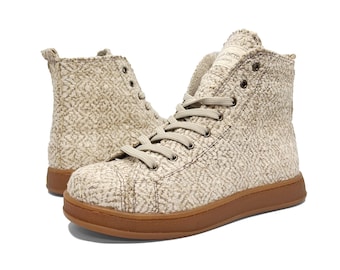 Puede incluir: Zapatillas altas de color beige con parte superior de tejido texturizado y suela de goma marrón.