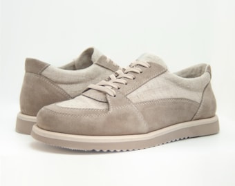 May include: A pair of light brown suede and canvas sneakers with white laces. The sneakers have a thick white sole.