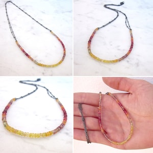May include: A multi-colored gemstone necklace with a gradient of red, orange, yellow, and green beads. The necklace is made with a silver chain and is shown in multiple positions.