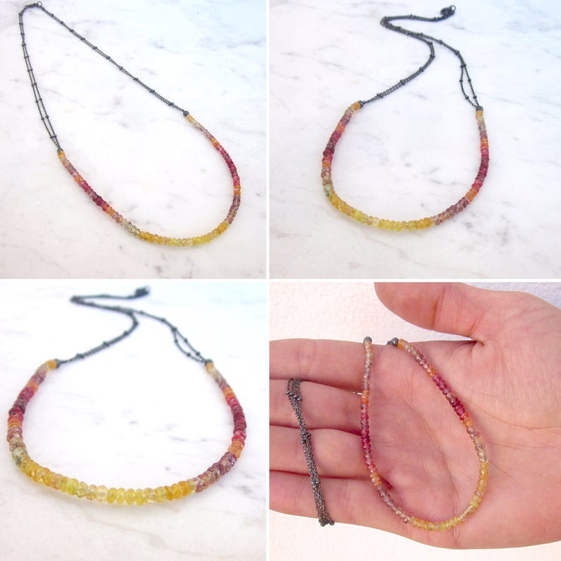 May include: A multi-colored gemstone necklace with a gradient of red, orange, yellow, and green beads. The necklace is made with a silver chain and is shown in multiple positions.